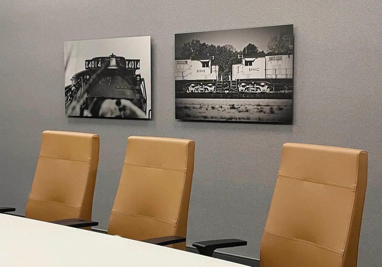 A conference room with three chairs and two paintings.